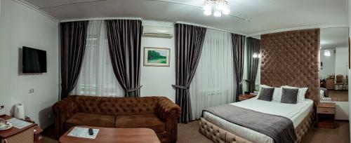 Habitación de hotel con cama y sofá en Kurmet Hotel, en Uralsk