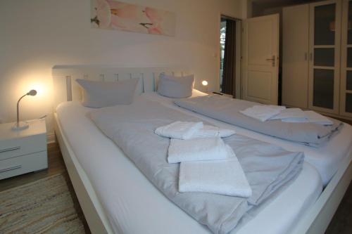 - un grand lit blanc avec des serviettes blanches dans l'établissement Am Flugplatz 7_ Haus Habel Whg_ 12, à Wyk auf Föhr