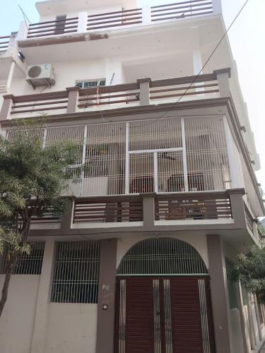 - un bâtiment blanc avec un balcon et une porte dans l'établissement Ved Vatika Homestay, à Faizābād