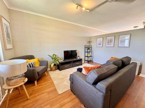 sala de estar con sofá y TV en Roomy Seaside Apartment, en Port Hedland