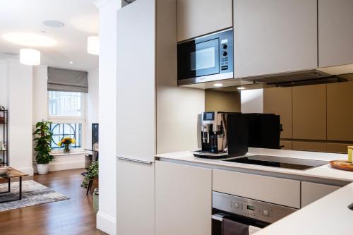 eine Küche mit weißen Schränken und einer Mikrowelle in der Unterkunft Elegant central London flat - ideal for weekend city break in London