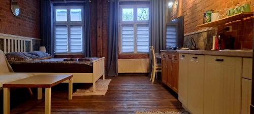 a room with a bed and a kitchen with windows at Staszica Starówka in Olsztyn