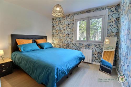 une chambre avec un lit bleu et une fenêtre dans l'établissement Luna, à Paimpol