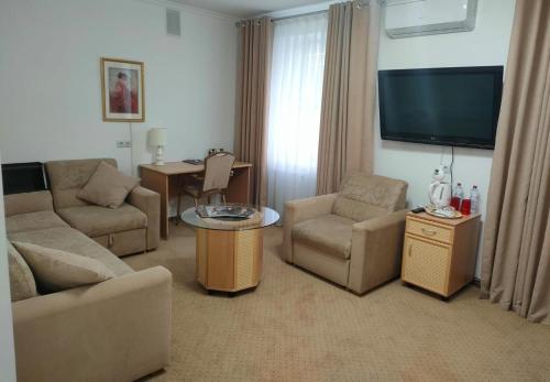 a living room with a couch and a tv at Kurmet Hotel in Oral