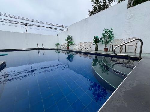 uma piscina com cadeiras ao lado de uma parede branca em Furutech Resort em Malolos