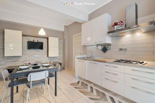 una cocina con armarios blancos y una mesa con sillas. en Valley House, en La Spezia