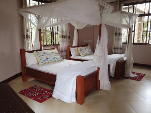 1 dormitorio con 2 camas y dosel en UPENDO MANYARA SAFARI LODGE en Mto wa Mbu