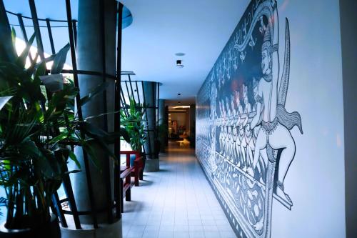 a hallway with potted plants and a painting on the wall at Siem Reap Palace Hotel & Spa in Siem Reap