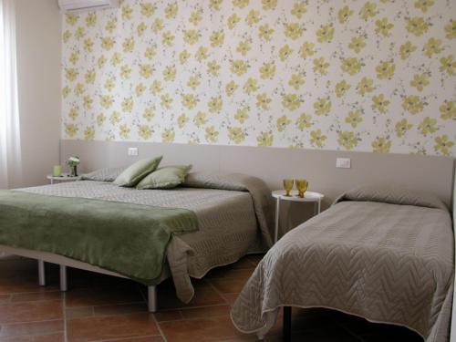 1 dormitorio con 2 camas y papel pintado con motivos florales en Agriturismo La Masseria - La casa tra gli alberi, en Cugnoli
