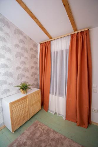 a room with a window with orange curtains at Natural e Simplu in Petroşani