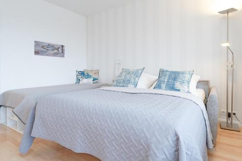 ein weißes Schlafzimmer mit einem großen Bett mit blauen Kissen in der Unterkunft Appartementanlage Kammerweg 5-5b Kleinaberfein in Scharbeutz