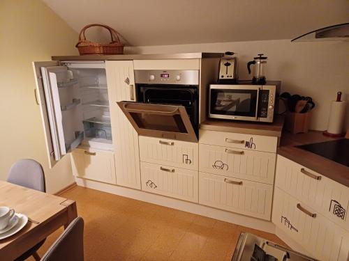 eine Küche mit einem offenen Kühlschrank und einer Mikrowelle in der Unterkunft Das Tor zur Rhön 