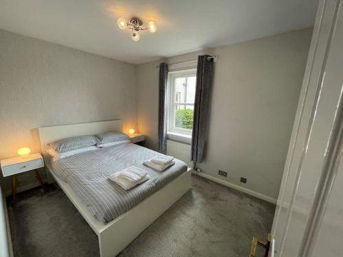 1 dormitorio con 1 cama con 2 toallas en 2 Bedroom Apartment near Glasgow Airport, en Renfrew