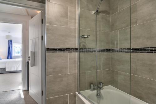 a bathroom with a shower with a bath tub at Finest Retreats - Teylu - Family home for 6 Adults and 3 children in Marhamchurch