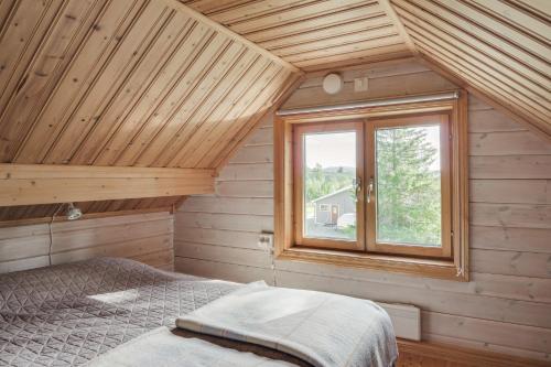 Cama en habitación de madera con ventana en Stuga i Funäsdalen en Funäsdalen
