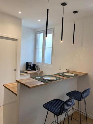 une cuisine avec deux tabourets de bar et un comptoir dans l'établissement Cozy modern studio, à Paris