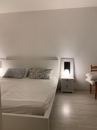 a white bedroom with a bed and a mirror at French Riviera apartment with swimming pool and free parking near Monaco in Roquebrune-Cap-Martin