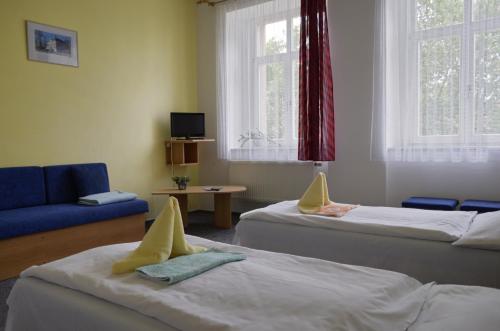 a room with two beds and a blue couch at Penzion Poodří in Suchdol nad Odrou