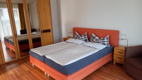 a bedroom with a bed with an orange headboard and a mirror at Wellness Ferienwohnung mit Bademantelgang zur Therme in Bad Griesbach