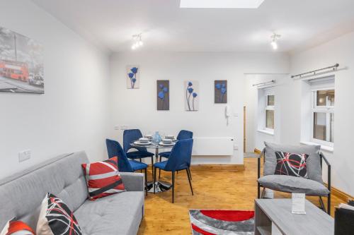 uma sala de estar com um sofá, uma mesa e cadeiras em Iconic London Apartment em Londres