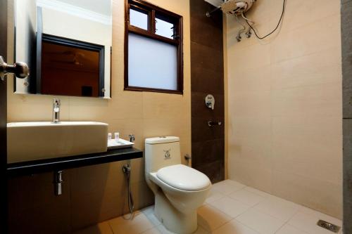 een badkamer met een toilet, een wastafel en een raam bij LA SAPPHIRE HOTEL & RESTUARANT in New Delhi