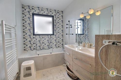 een badkamer met een bad, een wastafel en een spiegel bij Des faudours in Plérin