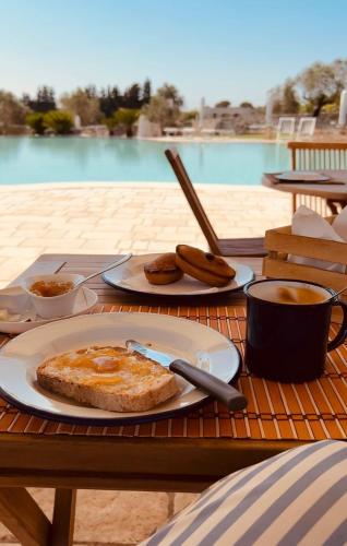 une table avec deux assiettes de nourriture et une tasse de café dans l'établissement Agriturismo Le Site, à Corigliano dʼOtranto