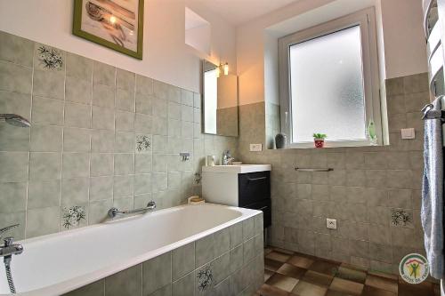 La salle de bains est pourvue d'une baignoire, d'un lavabo et d'une fenêtre. dans l'établissement Gite de la glanerie, à Coëtmieux