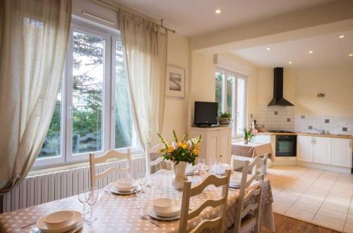 une salle à manger avec une table et des chaises ainsi qu'une cuisine dans l'établissement Les magnolias, à Fréhel