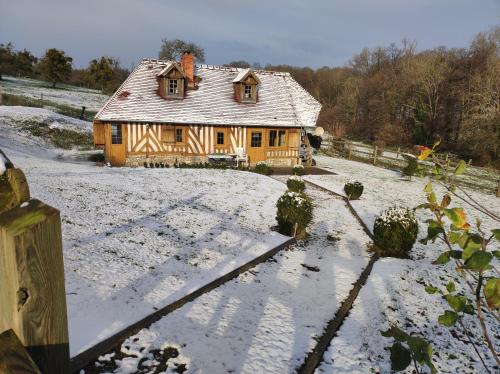 een huis in een met sneeuw bedekt veld met een hek bij La cour du manoir in Heuland