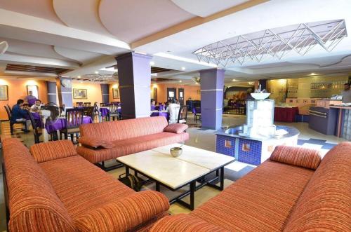 hol z pomarańczowymi kanapami, stołem i krzesłami w obiekcie Pak Continental Hotel w Bahawalpur