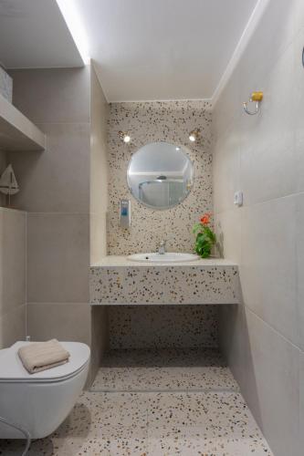 a bathroom with a sink and a toilet and a mirror at Camelot Royal Beds by Estia in Malia