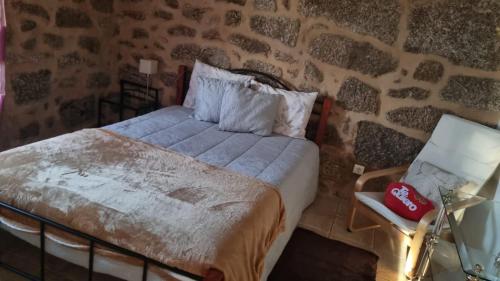 a bedroom with a bed and a stone wall at Turismo rural 4QUINTAS in Minhocal