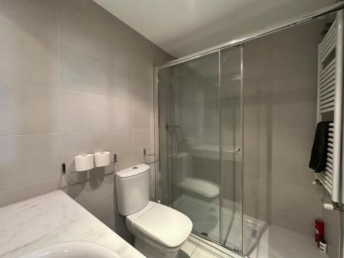 a bathroom with a toilet and a glass shower at Lujoso Loft La Moraleja in Madrid