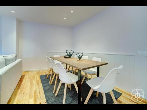 a dining room with a wooden table and white chairs at HONT de Alma de Nieve in Gessa