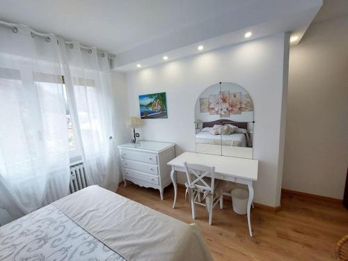 a bedroom with a bed and a desk and a mirror at Sunset House Perledo in Perledo