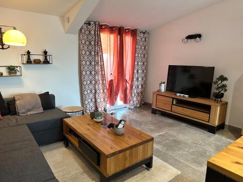 ein Wohnzimmer mit einem Sofa und einem TV in der Unterkunft Maisonnette Du Mas Vert in Montaren-et-Saint-Médiers