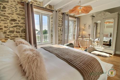 a bedroom with a large bed and a stone wall at Les pommettes in Plouër-sur-Rance