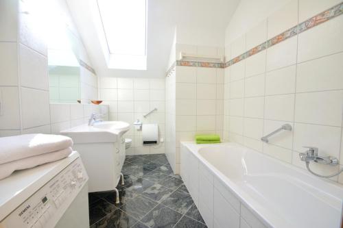 een witte badkamer met een bad en een wastafel bij Ferienwohnung Gartenblick am Schweriner See in Schwerin