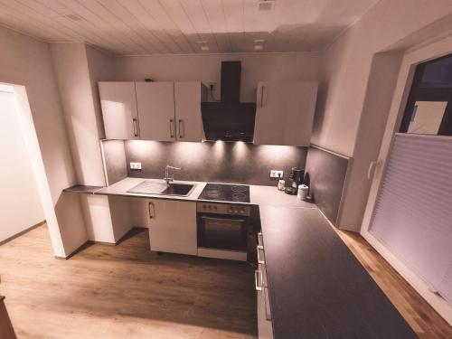 a small kitchen with white cabinets and a sink at Ferienwohnung Haßbergliebe in Ebern