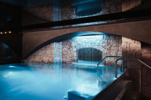 a pool of water in a building with a stone wall at Luxury Chalet P in Ortisei