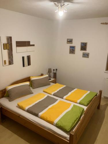 a bedroom with a large bed with yellow and green sheets at Appartement Ramona in Hainzenberg