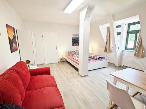 a living room with a red couch and a bed at UO3 - Urlaubsmagie- Urlaubsoase mitten in Sebnitz in Sebnitz