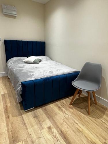 łóżko z niebieską ramą i krzesłem w obiekcie Dralda House w mieście Buckinghamshire