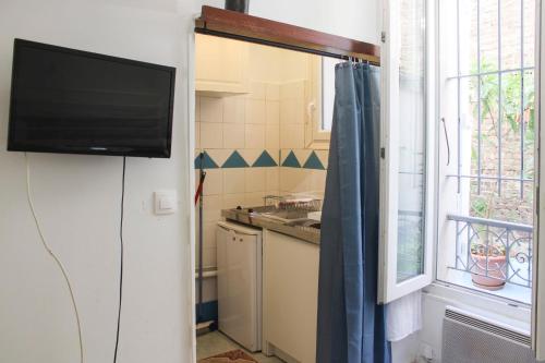 una pequeña cocina con TV y ventana en Bright studio located near Paris, en Pantin