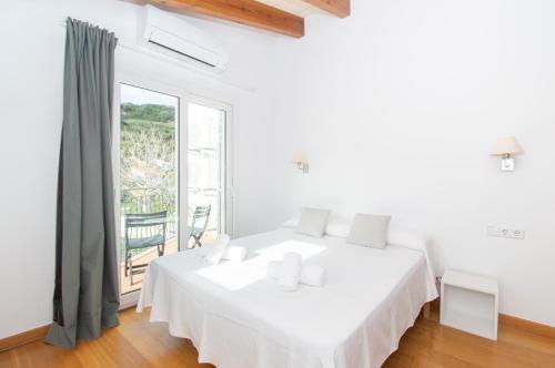 een witte slaapkamer met een bed en een groot raam bij Casa Lluminosa, fabulosa y moderna casa de pueblo by Sonne Villas in Ferreries