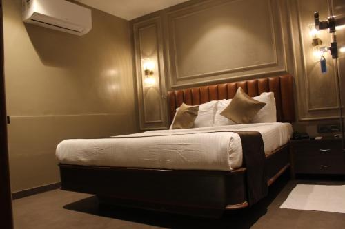 a bedroom with a bed with a wooden headboard at Gulf Hotel Mumbai- The Boutique Hotel Colaba Mumbai in Mumbai