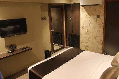 a bedroom with a bed and a flat screen tv at Gulf Hotel Mumbai- The Boutique Hotel Colaba Mumbai in Mumbai