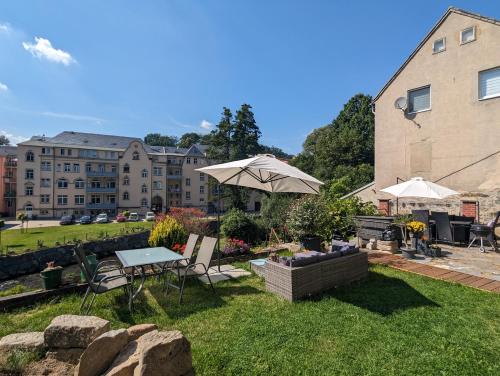 a backyard with a table and chairs and an umbrella at UO3 - Urlaubsmagie- Urlaubsoase mitten in Sebnitz in Sebnitz