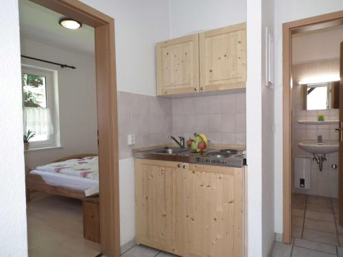 uma cozinha com armários de madeira, um lavatório e uma cama em Ferienwohnung Nexö, 30 qm, ein Schlafzimmer N1 em Ilsenburg